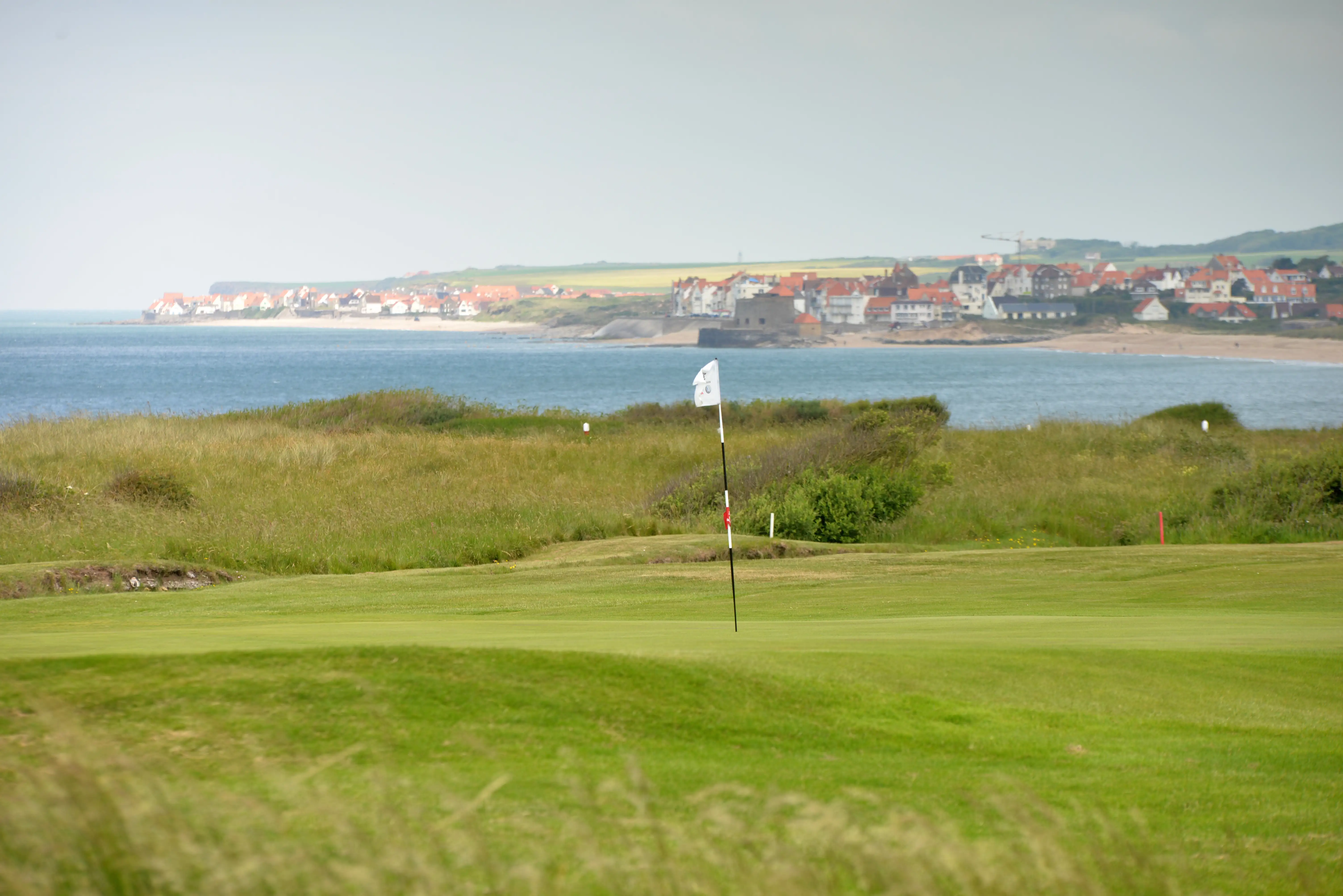 A flag in a green on a links golf course with sea views