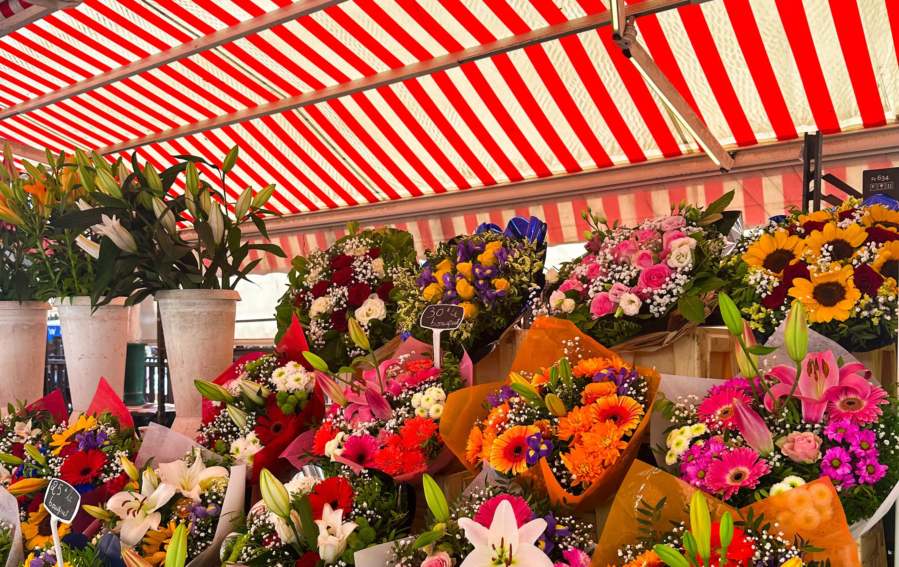 A vibrant flower stall at Nice’s market, filled with colourful bouquets under a striped red and white canopy.