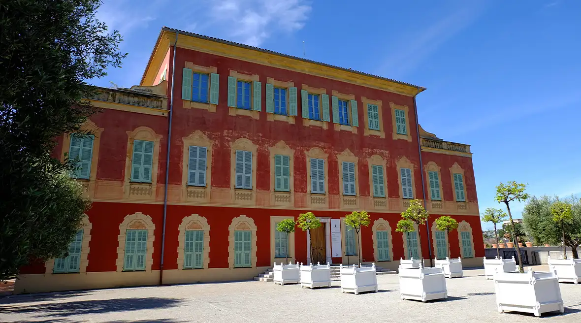 Exterior view of the Matisse Museum in Nice, France, showcasing the building surrounded by greenery on a cloudy day.